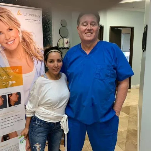 A client in a white sweater with James Hooper by the treatment banner