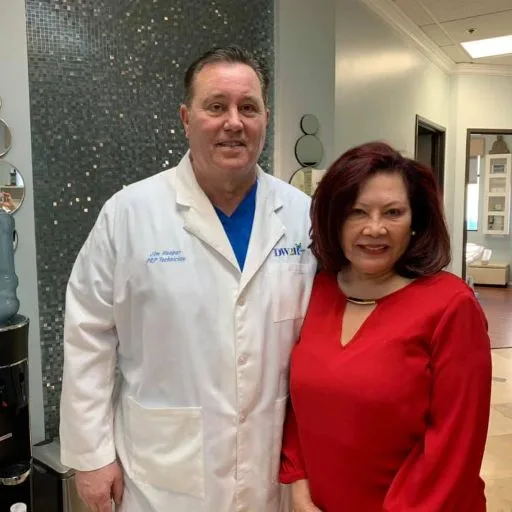 James Hooper in his lab coat with a client in a red dress
