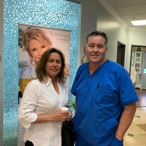 A client in a white blouse with James Hooper by the treatment banner