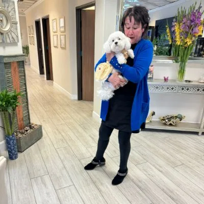 A guest holding a small white dog at the studio