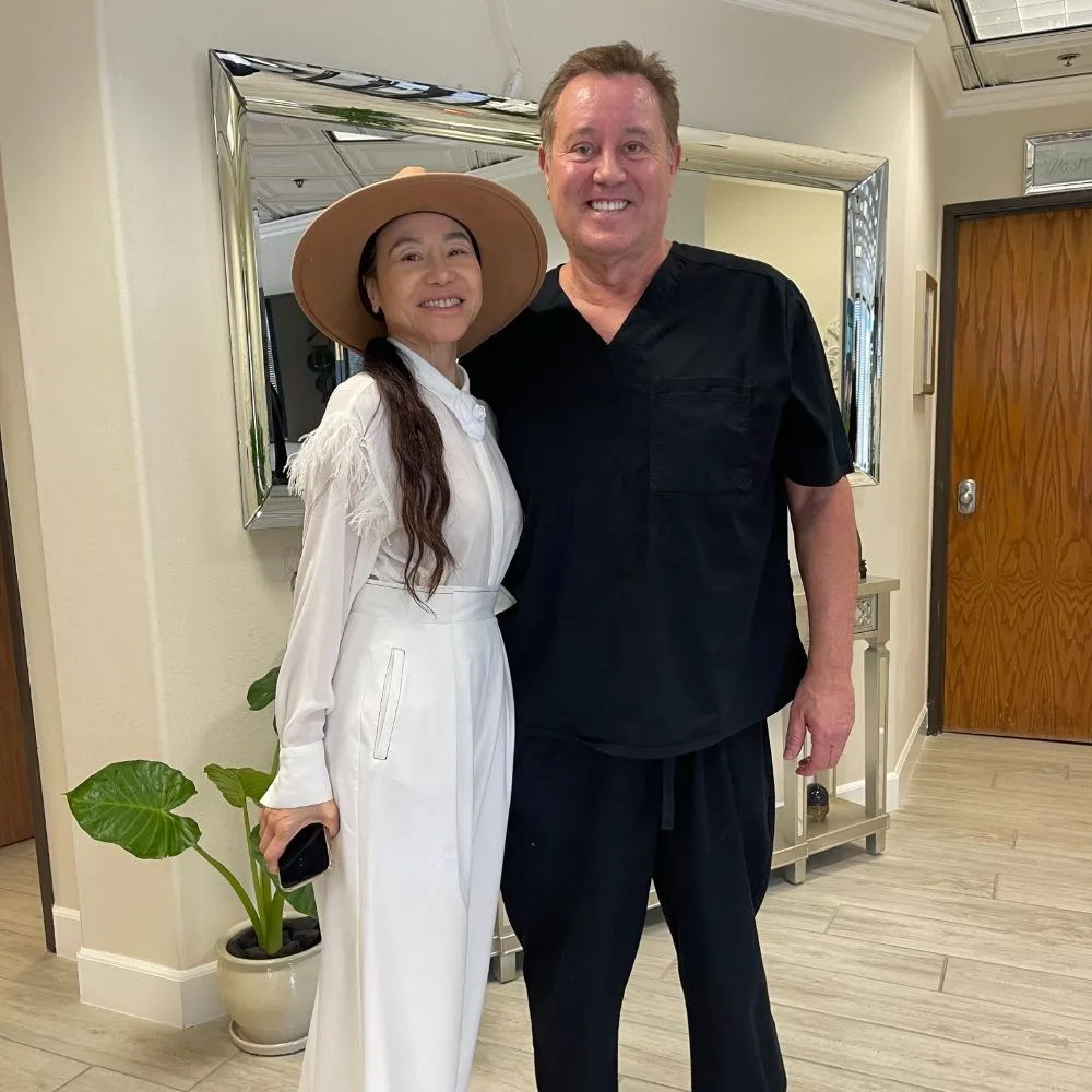 A client in a white dress and sun hat with James Hooper