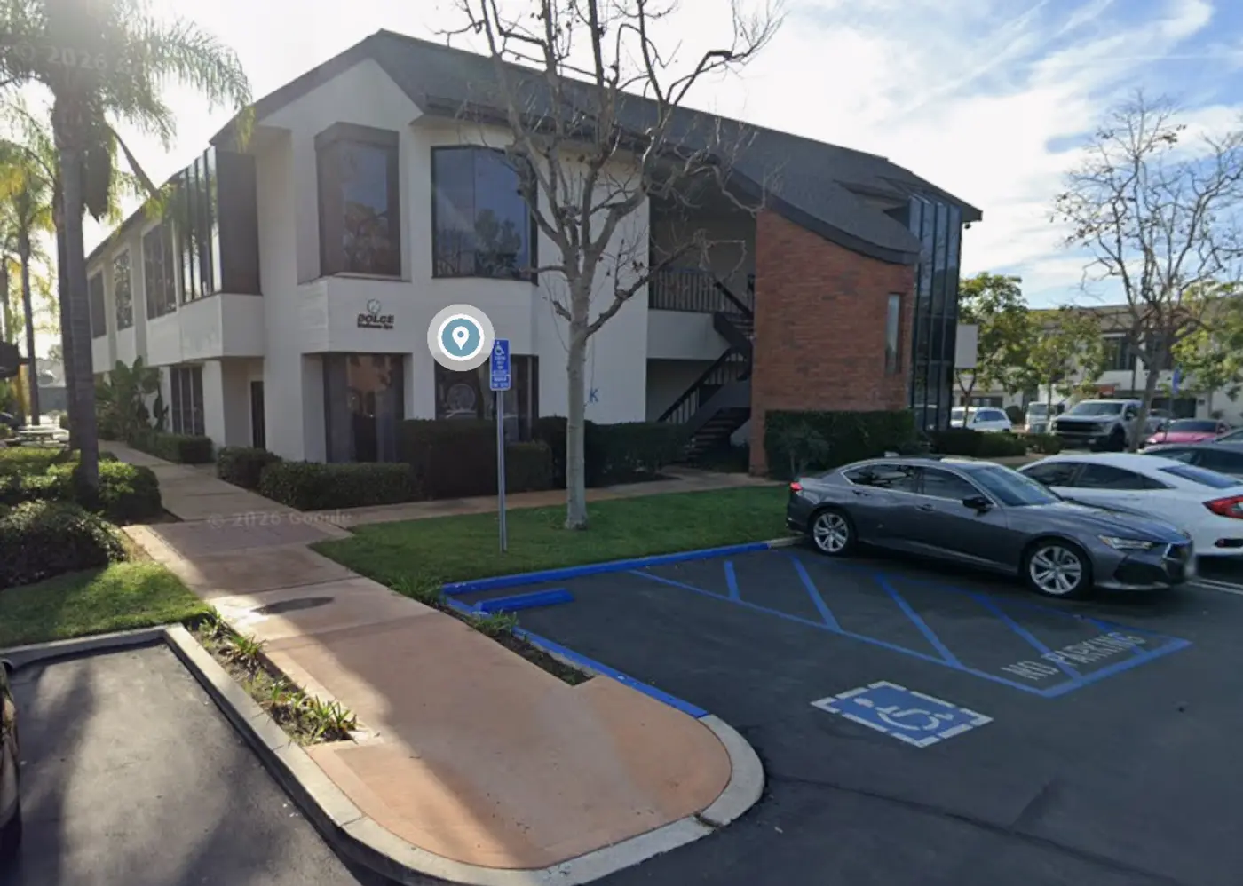 The two-story Bldg K106 office building at Newport Beach Skin Tightening's Costa Mesa location, with the walkway entrance and free parking spaces directly outside