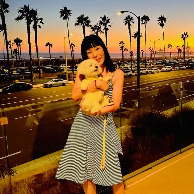 A guest holding Lulu at sunset with palm trees lining the coast highway behind them
