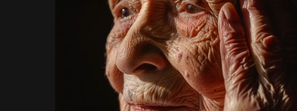an elderly woman gently pressing her cheek, showcasing visible signs of skin sagging and loss of firmness, under soft natural lighting.