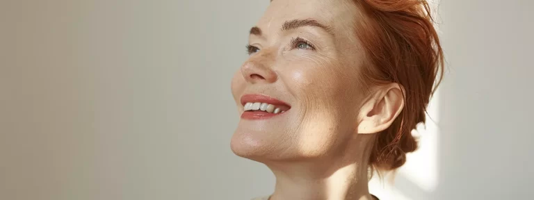 a woman with radiant skin and a lifted jawline smiles confidently after undergoing ultherapy, a premier non-surgical facelift alternative.